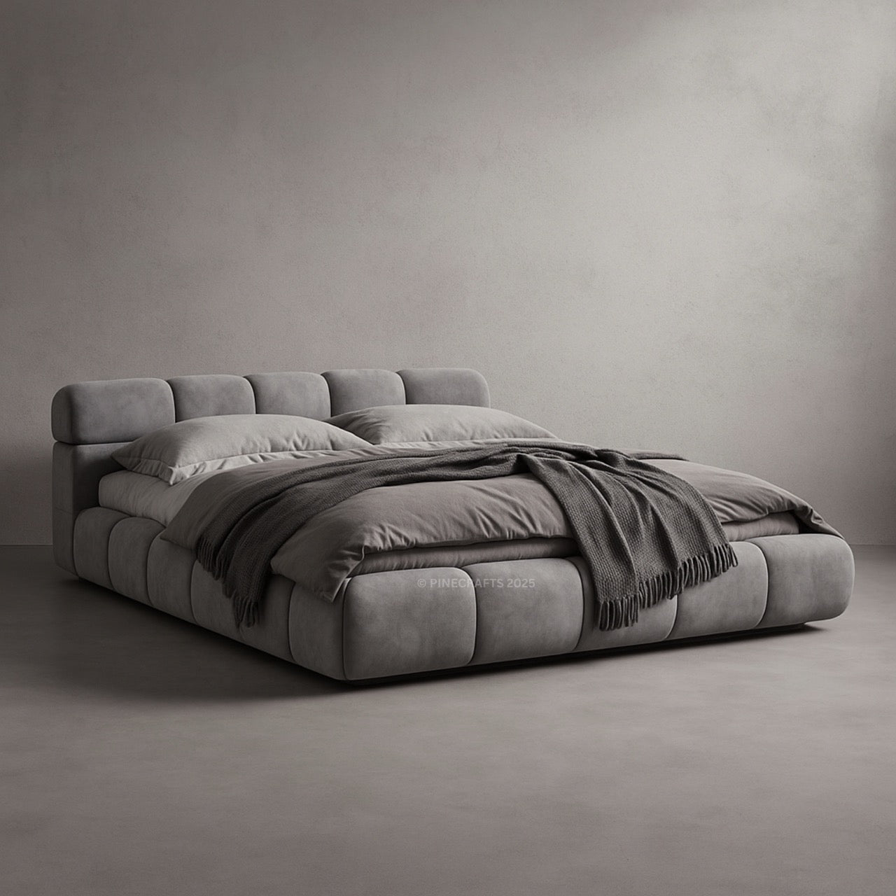 Gray upholstered bed with pillows and a blanket on a plain background
